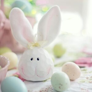 Charming Easter setup featuring a bunny decoration and pastel eggs on a floral tablecloth.