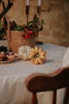 Cozy autumn tablescape featuring decorative gourds, pomegranates, and wicker accents, perfect for fall decor inspiration.