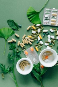 Basic supplements your body really needs Flat lay of assorted pills and herbs on green surface, symbolizing health and wellness. Flache Anordnung verschiedener Pillen und Kräuter auf grüner Oberfläche, symbolisch für Gesundheit und Wohlbefinden. Ploché rozložení různých pilulek a bylin na zeleném povrchu, symbolizující zdraví a pohodu.