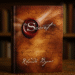 CZ: „Detailní fotografie knihy Tajemství (The Secret) od Rhondy Byrne stojící na dřevěném stole před rozostřenou knihovnou.“ EN: “Close-up photograph of the book The Secret by Rhonda Byrne standing on a wooden table in front of a blurred bookshelf.” DE: „Detailfotografie des Buches The Secret von Rhonda Byrne, das auf einem Holztisch vor einem unscharfen Bücherregal steht.“
