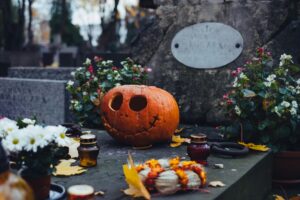  dýně na hrobě obklopená květinami a svíčkami na varšavském hřbitově.  A pumpkin on a grave surrounded by flowers and candles in a Warsaw cemetery.