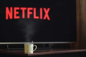 Každá hodina před televizí nebo mobilem tě stojí kousek života. Hrnek s kávou na stole před televizí, na které běží Netflix, vytváří útulnou atmosféru v interiéru.