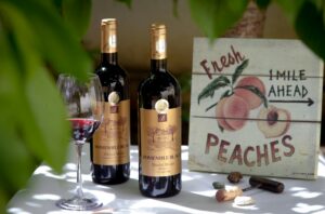 Two bottles of Romanian wine and a glass on a table with a vintage peaches sign.