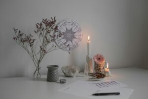 wheel of the year / kolo roku A serene desk setup with candles, crystals, and a wheel of the year decoration.