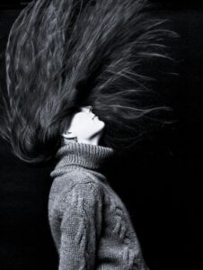Monochrome photo capturing dramatic motion of woman's hair in dynamic pose.