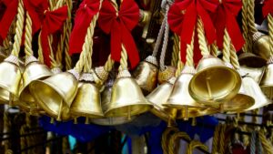 A collection of golden bells hanging with red ribbons, creating a festive and decorative scene.