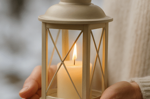 Ruce ženy jemně drží světlou lucernu s hořící svíčkou v zimním prostředí — symbol Betlémského světla a klidu.
