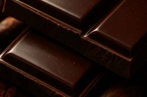 Makro detail lesklé hořké čokolády s kakaovými boby a dramatickým osvětlením.