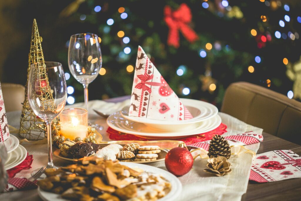 Beautifully set Christmas table with decorations, food, and drinks under festive lights.