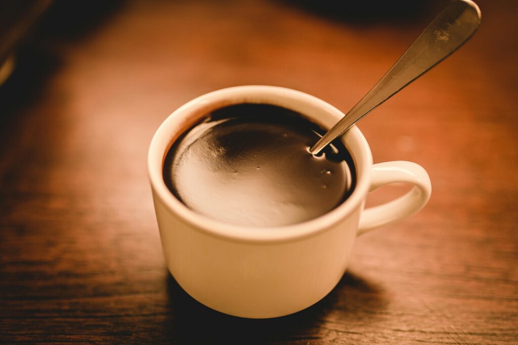 A cozy image of a hot coffee cup with a spoon on a wooden table, perfect for a cozy atmosphere.