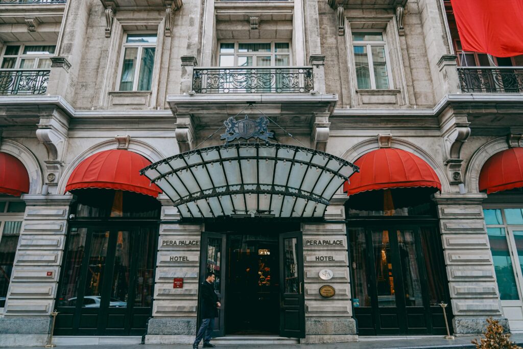 Front view of the iconic Pera Palace Hotel facade in Istanbul with red awnings and ornate entrance.