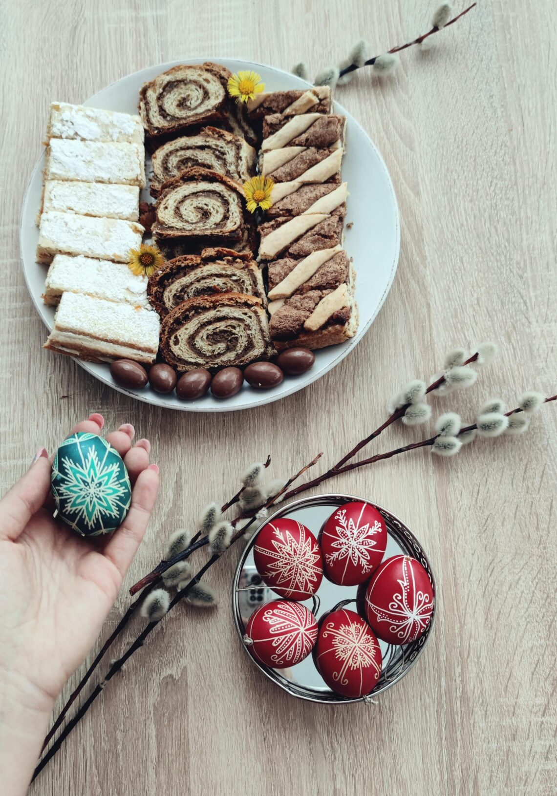 A high-angle shot of Easter pastries and beautifully decorated eggs on a wooden table, perfect for holiday inspirations.
