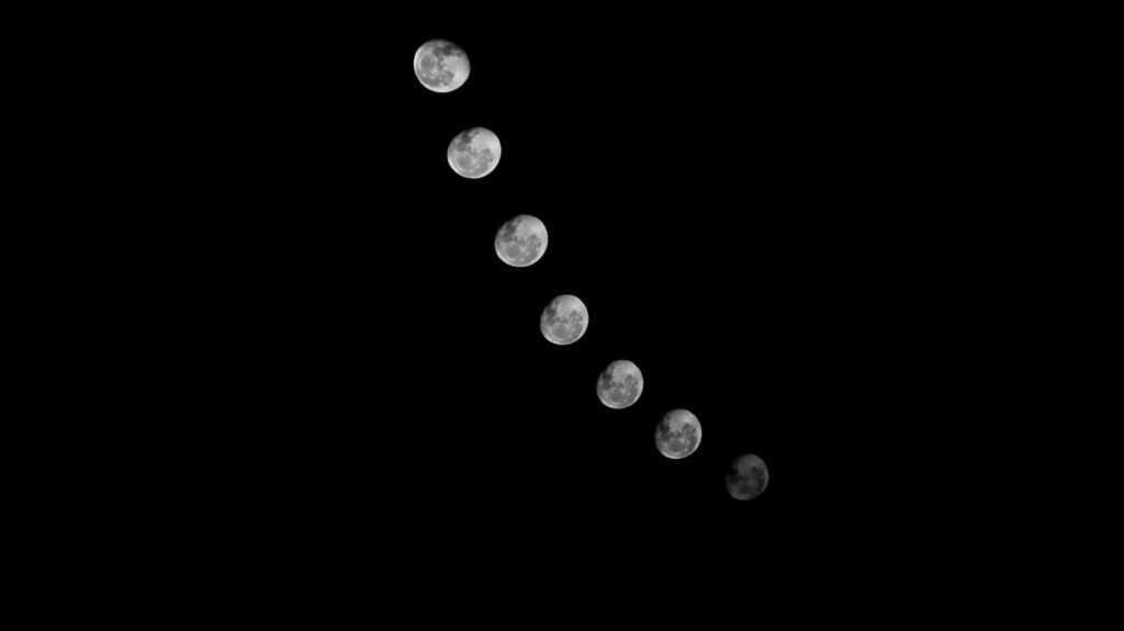 novoluní, fáte měsíce, novoluni v raku, new moon, Black and white photo showing the phases of the moon against a dark night sky, creating a celestial scene.