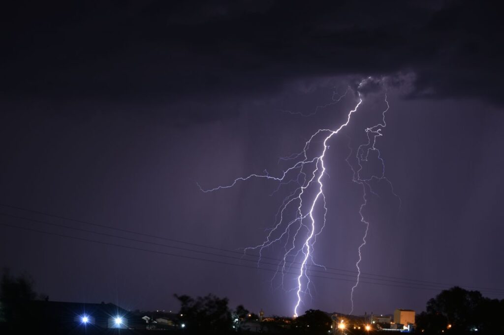 Bouřka, vyčištění energie, čistý vzduch, Powerful lightning strike illuminates the night over a South African landscape, showcasing nature's fierce beauty.