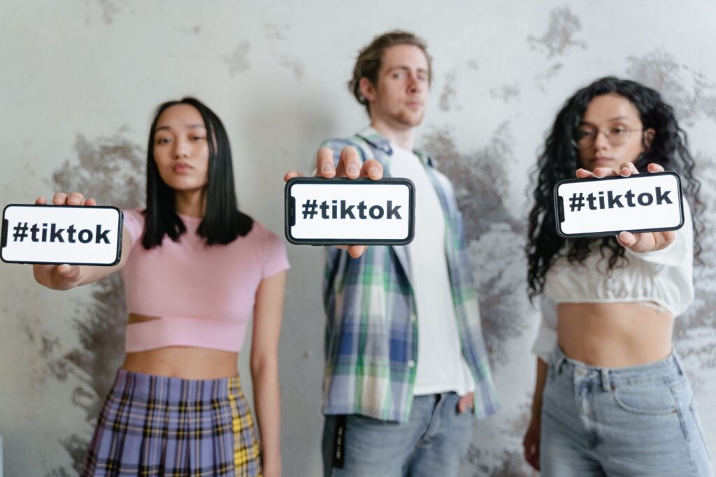 SOCIÁLNÍ SÍTE, odborníci, videa, algoritmus, Group of young adults holding phones with #tiktok indoors, showcasing social media culture.